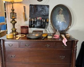This vintage five drawer chest measures 21" x48". On the wall below the mounted deer horns is a Victorian toiletries kit.  Each item is monogramed. There are other samples of Victorian items on the dresser such as celluloid handheld mirror.