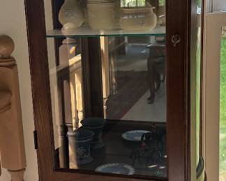 Tall, slender lighted display cabinet full of Wedgwood and Waterford