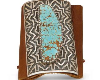409
A Dan A. Jackson Navajo Silver And Turquoise Ketoh Bow Guard
Dan A. Jackson (1944-2022, Diné)
Late 20th/21st century
Stamped: D. A. Jackson
Centering a silver plaque with high relief inlaid geometric pattern set with a large #8 turquoise stone, mounted on a soft leather band with leather ties
4" H x 2.5" W
208.8 grams gross
Estimate: $500 - $700