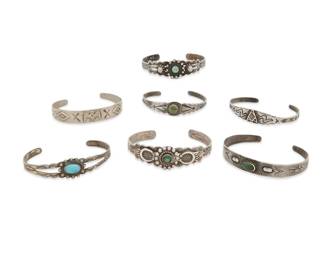 415
A Group Of Fred Harvey Silver And Turquoise Cuff Bracelets
Early/mid- 20th century
One marked: Nickel Silver / Bell; one marked: Silver Products / Coin silver [with an arrow]
Comprising seven diminutive narrow silver cuffs, five with set turquoise and greenstone, and all in various styles and sizes, with motifs including stampwork, arrowheads, thunderbirds, rattlesnakes, and crossed arrows, 7 pieces
Largest: 6.125" inner C x 0.75" H, with a 1" gap; smallest: 5.5" inner C x 0.5" H, with a 0.875" gap
67.2 grams gross
Estimate: $700 - $900