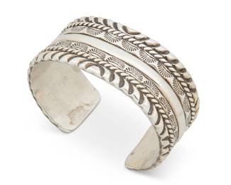 405
A Southwest Silver Cuff Bracelet
Mid-20th century
Stamped: W
A chunky cuff with multiple bands of stampwork, twisted wire, and incised silver edges
6.75" inner C x 1.125" H, with a 1" gap
109.8 grams
Estimate: $400 - $600