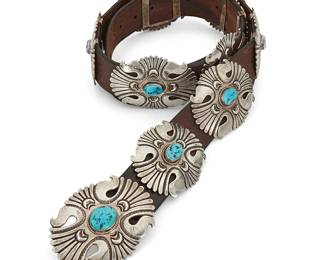 433
A Leonard Gene Navajo Sterling Silver And Turquoise Concho Belt
Mid/late 20th century
Stamped: G [over an arrow either side] / Sterling
A chunky belt with a large oval stamped and incised silver concho buckle with set oval turquoise and ten smaller matching conchos, all mounted to a commercial leather belt
Buckle: 2.375" H x 3.125" W; each concho: 2.25" H x 3.125" W; belt: 44.5" L x 1.5" H
680.8 grams gross
Estimate: $800 - $1,200