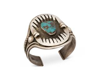 386
A Southwest Silver And Turquoise Cuff Bracelet
Mid/late 20th century
Etched verso: 87
A chunky cuff with large oval shadowbox plaque with jagged bearpaw-style surround and central set turquoise, with rope wire accents
6.125" inner C x 2.25" H, with a 1" gap
52.2 grams gross
Estimate: $300 - $500