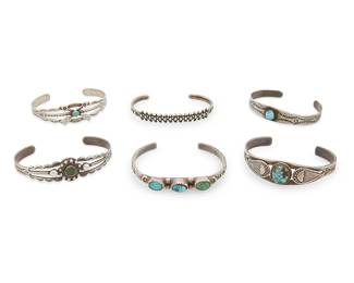 413
A Group Of Fred Harvey Silver And Turquoise Cuff Bracelets
Early/mid-20th century
One marked for sterling
Six narrow silver cuffs, five with set turquoise, and all in various styles and sizes, with motifs including stampwork, arrowheads and crossed arrows, 6 pieces
Largest: 6.5" inner C x 0.625" H, with a 1.25" gap; smallest: 6" inner C x 0.5" H, with a 1.125" gap
83.4 grams gross
Estimate: $700 - $900