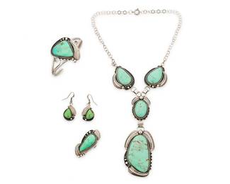 370
A Set Of Southwest Navajo Sterling Silver And Variscite Jewelry
Late 20th century
Each stamped: R. Charley / Sterling
Four works with set green variscite in elaborate settings with applied silver feathers, shadowbox and silver ball accents, comprising a pendant necklace, a two-wire cuff bracelet, a ring, and a pair of earrings, 5 pieces
Necklace: 17.25" L x 5" H; cuff: 7" inner C x 1.75" H, with a 1.125" gap; ring: size: 7.5; each earring: 1.75" H
108.8 grams gross
Estimate: $400 - $600