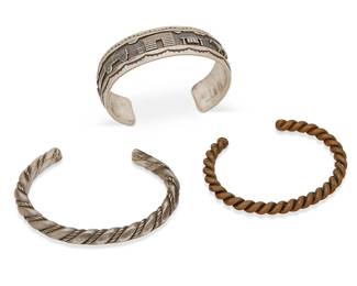 418
A Group Of Southwest Cuff Bracelets
Early/mid-20th century
One stamped: RH Begay / Sterling
Three works comprising a chunky Roland Hogan Begay (Navajo/Diné) storyteller cuff, together with a twisted silver narrow cuff bracelet, and an early twisted copper wire cuff bracelet, 3 pieces
Largest: 6.5" inner C x 0.75" H, with a 1.25" gap; smallest: 6.125" inner C x 0.25" H, with a 1.125" gap
116.7 grams gross
Estimate: $300 - $500