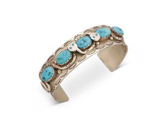 383
An Effie Calavaza Zuni Turquoise And Silver Cuff Bracelet
Effie Calavaza (b. 1927, Zuni Pueblo)
Mid/late 20th century
Stamped: Effie C / Zuni
A banded cuff with five set turquoise stones amidst applied snakes and stamped edges
6.25" inner C x 0.75" H, with a 1.5" gap
47.7 grams gross
Estimate: $300 - $500
