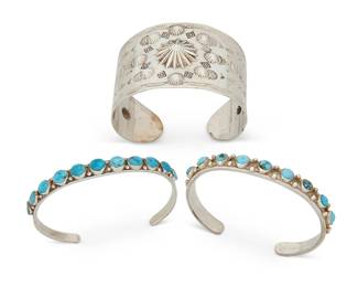 406
Three Southwest Silver Cuff Bracelets
Mid/late 20th century
Each unmarked
Comprising a wide silver repoussé cuff with stamped accents, as well as two narrow cuffs, each with row set turquoise and stampwork edging and accents, 3 pieces
Largest: 7" inner C x 1.875" H, with a 1" gap; smallest: 6.5" inner C x 0.25" H, with a 1.25" gap
107.2 grams gross
Estimate: $500 - $700