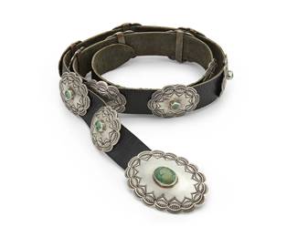 
430
A Southwest Silver And Set Turquoise Concho Belt
Late 20th century
Buckle stamped: MT / DJ [unknown makers]
A long belt with a large oval concho buckle with elaborate stampwork and a central set turquoise stone, with twelve smaller matching oval conchos, all mounted to a black leather strap
Buckle: 2.25" H x 3" W; each concho: 1.5" H x 2" W; belt: 39" L x 1.25" H
360.9 grams gross
Estimate: $800 - $1,200