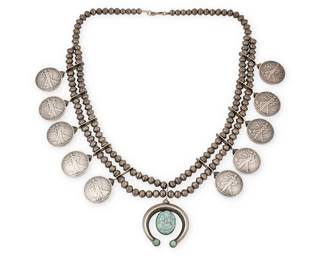 353
A Southwest Squash Blossom Necklace
Mid-20th century
Unmarked
A double strand of silver beads suspending ten Walking Liberty silver dollars and finished with a sand cast silver naja accented with a large oval turquoise stone
28" L x 2.75" H
228.5 grams gross
Estimate: $800 - $1,200