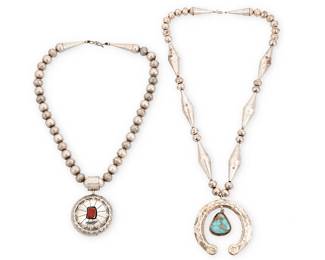 358
Two Southwest Silver Pendant Necklaces
Mid/late 20th century
Domed pendant marked to bail interior: LN / Sterling
Comprising a removable large round domed sterling silver spinner pendant with set coral to one face and an eagle dancer motif verso, suspended from a strand of round silver beads with alternating stamped motifs (20" L x 2.75" H), together with a large fixed turquoise drop naja pendant suspended from a strand of alternating stamped cone and ball beads (24" L x 2.75" H), 3 pieces
183.0 grams gross
Estimate: $600 - $800