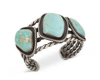 395
A Large Southwest Silver Cuff Bracelet
Early/mid-20th century
Stamped to terminal: Sterling
A chunky cuff with three large turquoise domed cabochons shadowbox-set to a four twisted wire cuff
7" inner C x 1.75" H, with a 1.25" gap
118.8 grams gross
Estimate: $400 - $600