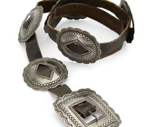 437
A Southwest First-Phase Style Silver Concho Belt
Mid-20th century
Unmarked
Comprising a stamped rectangular buckle with six stamped oval conchos all mounted on a dark brown leather strap
Buckle: 2.625" H x 3.125" W; each concho: 2.5" H x 2.75" W; belt: 35.5" L x 0.625" H
240.9 grams gross
Estimate: $800 - $1,200