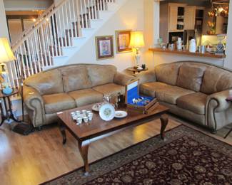 Leather couches with brass nail head accents. Back pillows are attached with zippers. 