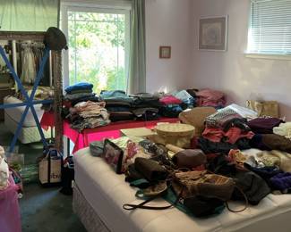 This photo shows lots of handbags, a large mirror, and bedding, all for your perusal.