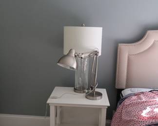 one of two white nightstands, one of two glass base lamps, one desk lamp