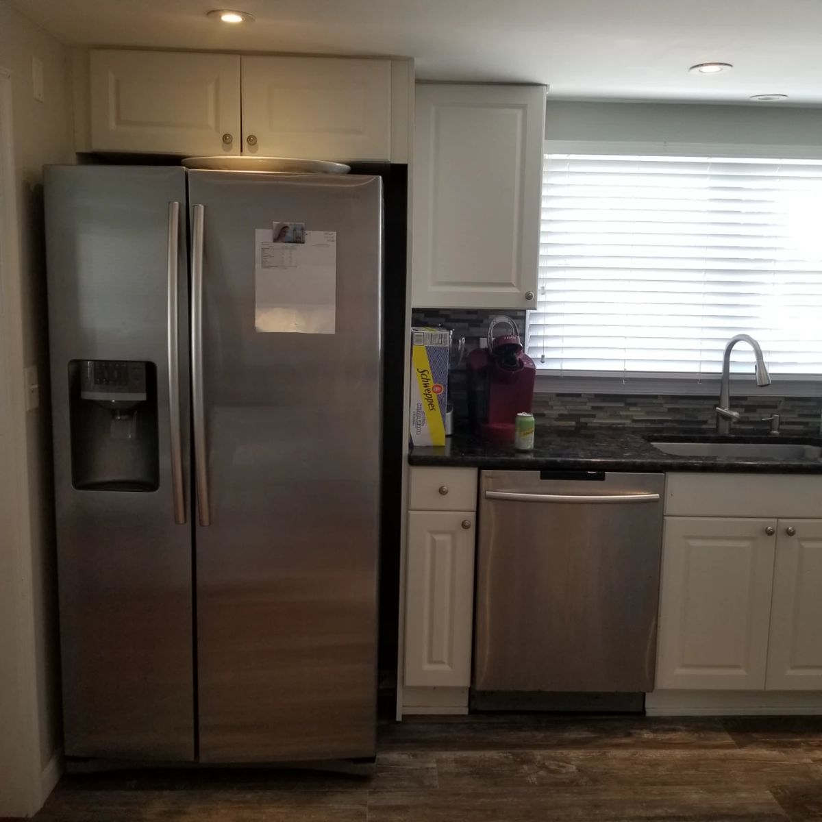 Crisp white kitchen with stainless steel appliances and black granite countertops