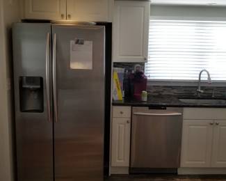 Crisp white kitchen with stainless steel appliances and black granite countertops