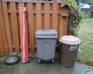 Garbage cans, one little one and one medium sized one, and an umbrella and an umbrella stand