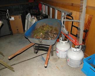 A lake rake, and extension ladder, some propane tanks, and a wheel barrow