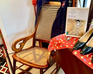 ANTIQUE CANED ROCKER. NOTICE THE OPEN TRUNK BEHIIND.