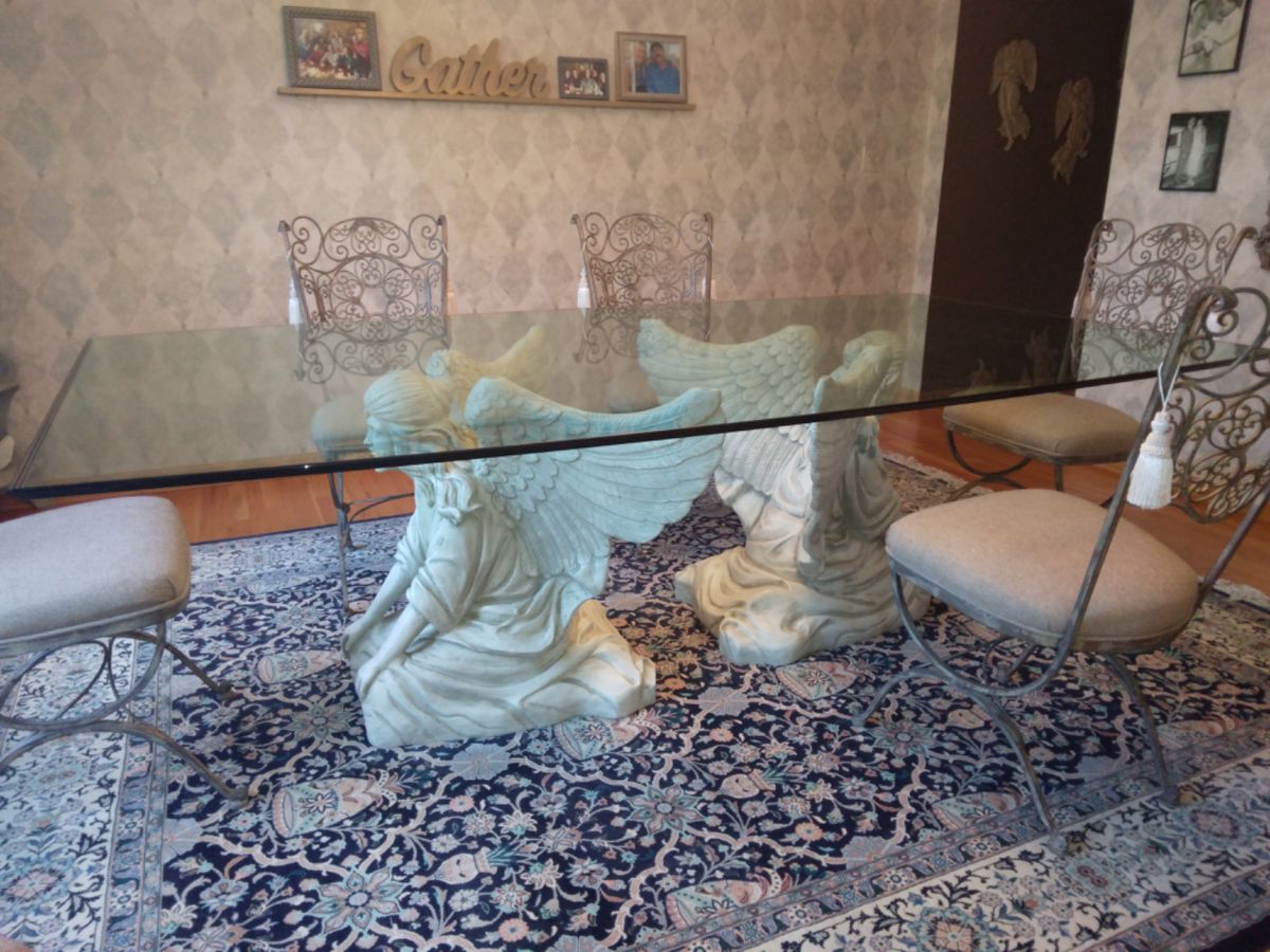 Unique FUNCTIONAL ART!  This is a custom made, one-of-a-kind gorgeous Angelic Dining Table.  
Twin angels kneel quietly under this unique and original glass top table.  Sculpted with the utmost care and attention to detail.  Featuring  intricate details on their wings and hair.  Lavishly clothed in flowing gowns.  
Elegant triple waterfall edge finish on boat shaped ¾” thick glass top.  Seats up to 12 people.  Base 29” Tall.  Wingspan  36”  Glass top 4’ X 8’.
Includes 12 wrought iron dining room chairs finished in a light bronze and cream colored cloth seats.  Beautiful scrolls and details on chair back.
A beautiful and unique dining room table to bring a little heaven to your family gatherings.
Includes original architectural drawings signed by the artist.  If you want a table NO ONE else in the world has, this one is for YOU! 