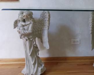 Angel  Sofa Table Twin angels with cherub create this unique sofa table.  Very unique and beautiful. Gorgeous feather details exquisite facial features on mother and cherub.
Fiberglass/resin.  Antique Stone.  Elegant triple waterfall edge finish on rectangle ½”  thick glass top.  Base 28” Tall.  Glass top measures 14” X 48”.  
