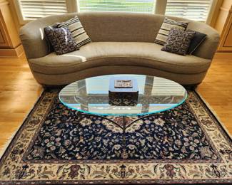 A beautiful Curved Grey/Wheat Toned Sofa. Glass Top Coffee Table. Handknotted Carpet. 