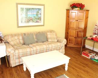 Upholstered sofa, white wood coffee table, corner cabinet.