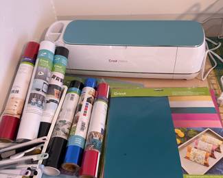 Cricut Maker with many vinyl rolls and paper reams