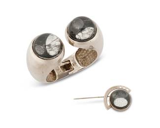 2026
A Set Of Modernist Silver Jewelry
Early 20th century
Each stamped: Sterling
Two works comprising a heavy hinged cuff bracelet with clear domed oil-filled cabochon terminals, together with a similar design abstract stick pin, 2 pieces
Bracelet: 6" inner C x 1.125" H; pin: 2" H (with pin) x 1" W
155.6 grams gross
Estimate: $300 - $500