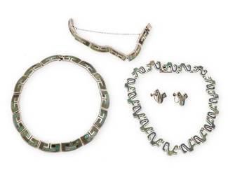 2220
A Group Of Los Castillo Mexican Silver And Stone Inlay Jewelry
Circa 1950-1965; Taxco, Mexico
Each variously stamped: Los Castillo / Taxco / Sterling / Made in Mexico / 925 / [Eagle 15] / Mosaico Azteca / [design numbers: 170, 233]
Four works in sterling silver and greenstone inlay comprising a Mosaico Azteca narrow link necklace with hooked motif, together with a matching link bracelet, as well as a Mosaico Azteca abstract "V" motif link necklace and a pair of similar design earrings, 5 pieces
Larger necklace: 15" L x 0.5" H; smaller: 14" L x 0.625" H; bracelet: 6.5" L x 0.5" H; each earring: 0.75" H
190.0 grams gross
Estimate: $400 - $600