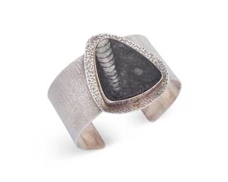 2024
A Candy Caldwell Sterling Silver And Set Stone Cuff Bracelet
Late 20th/21st century
With etched signature verso, further stamped: Sterling
A wide textured silver band cuff with stamped central triangular plaque featuring a bezel-set fossil stone
6.6" total inner C x 2" H, with a 1.125" gap
70.4 grams gross
Estimate: $200 - $400