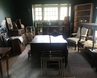 Room full of desks, tables, mirrors, large speaker, art, window frame and chair.