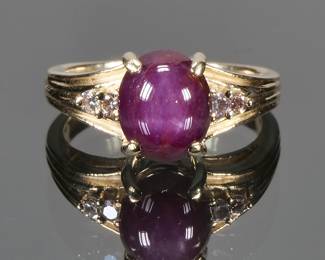 NATURAL PURPLE STAR SAPPHIRE, DIAMOND & GOLD RING | Designed as a central purple star sapphire (9.1 x 7.6 x 5.95 mm), flanked by two melee diamonds in a fluted (tested to) 14k gold setting; size 6., 5.6g total weight; no apparent markings.
