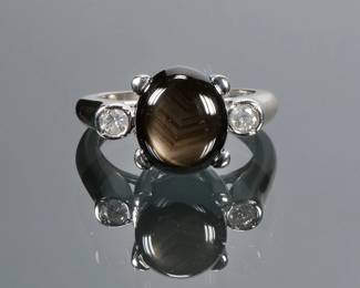 BLACK QUARTZ CABOCHON, DIAMOND & 14K GOLD RING | Designed as a central phenomenal black quartz (11 x 9.2 x 5 mm) flanked by two full cut diamonds and set in (tested to) 14k white gold; Size 5, 5.8g.
