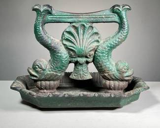 19TH C. DOLPHIN FORM CAST IRON BOOT SCRAPE | An early boot scraper decorated with dolphins (fish) and a central seashell and with old green paint - l. 14 x w. 10 x h. 10 in.