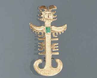 18K EMERALD FIGURAL PIN | Designed as a pierced textured gold figural pin with Mayan or Aztec figure mounting a central rectangular faceted emerald 1.75 in., 3.3g; marked "18k".