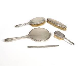 (5pc) CONTINENTAL SILVER DRESSER SET | A four piece continental 800 silver dresser set comprising a hand mirror, two brushes, and a comb handle, each marked "800"; plus a separate sterling handled brush of small size; weighable silver 0.6 ozt (comb handle only) - l. 12.5 in. (mirror)