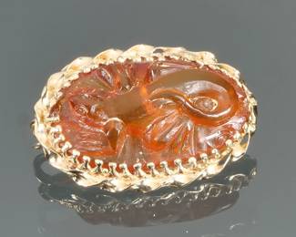 CARVED AMBER & 14K GOLD PIN | Designed as an oval carved Amber pin with a lizard or salamander in high relief in a twisted rope work surround; 1 in., 3.8g; marked with a "G" and tested to 14k.
