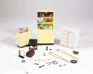 DOLLHOUSE DOCTOR'S OFFICE GROUP | Dollhouse miniature furniture for a doctor's office, including a yellow painted cabinet with doctor's accessories (jars, jar of iodine, test tubes, etc.) and a matching bookcae with books, diapers, and toys; plus a white painted cabinet, a first aid kit, microscopes, leather doctor's bag, crutches, cast, bottle of Bayer with floating tablets inside, and others
 - l. 3-3/8 x w. 2-5/8 x h. 6-1/2 in. in. (bookcase)