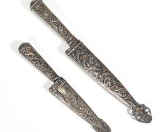 (2pc) 19TH C. ARGENTINA GAUCHO SILVER FIGHTING KNIFE / DAGGERS | Including a knife with a chased repousse 800 silver handle and sheath decorated with flowers and scrolls and with gold gilt highlights, belt clip marked "MD ARG. 800" the blade marked "---OVEDIZA IND. ARG__"; (blade 7.25 in. overall 12.75 in.); plus a similar smaller dagger with pressed flowers and scrollwork with no apparent maker or fineness marks, sheath stamped "ALPACA" (9.5 in., overall)
