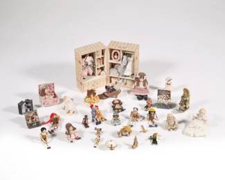 MINIATURE DOLL TRUNKS & DOLLS | A collection of miniature toy dolls and wooden puppets for a dollhouse playroom or child's room, including: a floral patterend trunk with opening drawer, housing a doll, clothes, and boxes; a white basket with doll and accessories; a tiny fancy doll in a blue leather trunk; a doll in a domed egg-like keepsake box, signed with initials LGY; and two filled miniature toy trunks, each signed on the bottom "LIGIA.GY" (?); plus several loose dolls, including with a matching rocking horse; and a collection of articulating miniature wooden puppets, some with strings  - l. 2.5 x w. 2.25 x h. 3.75 in. (largest trunk)