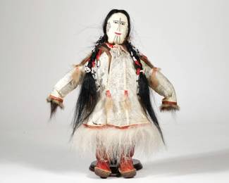 NATIVE ALASKAN SEALSKIN DOLL | Savoonga sealskin, hair, and fur doll with leather boots and face, fur pants, and sealskin coat, the face decorated with traditional tattooing, with tag attached identifying the artist as Elaine Kingeekuk - l. 13 x w. 10 in.