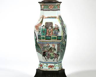 A CHINESE FAMILLE VERTE HEXAGONAL LAMP | Hexagonal baluster form vase mounted as a lamp; 15.5 in. (ceramic only), with a tsuba form finial, decorated with figures and flowers in various scenes; drilled - l. 9 x w. 8 x h. 39 in. (over harp)
