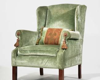 VELVET UPHOLSTERED WINGCHAIR | Finely upholstered in green velvet with scroll arms, tassels on the handholds, accompanied by a matching velvet pillow - l. 31 x w. 28 x h. 41 in.
