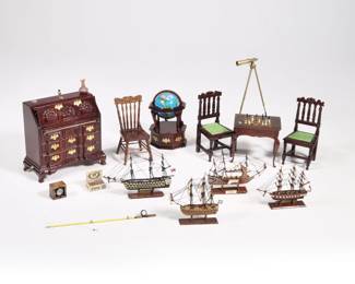 (14pc) DOLLHOUSE DEN FURNITURE | Miniature dollhouse furniture for a den, including: a drop front desk, with slide out supports and functioning drawers, decorated with miniature art glass, sextant, and other accessories, a miniature chess table and two carved wood chairs, a globe on stand, four miniature ship models, a ship's compass, box of cigars, brass telescope on a tripod stand, a fishing pole, and a spindle back chair  - l. 3.75 x w. 2 x h. 3.75 in. (desk closed)