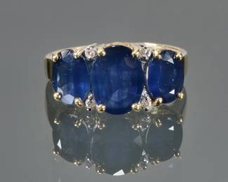TRIPLE SAPPHIRE & 14K GOLD RING | Designed as a central oval mixed cut sapphire (9 x 6.7 x 3.7mm), flanked by two smaller oval mixed cut sapphires and four melee diamonds, set in a 14k gold band (size 5, 3.8g); marked "14k" and with "V | P" makers mark
