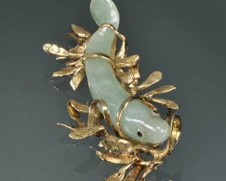 CARVED JADE FISH & 14K GOLD MOUNTED PENDANT | Designed as a carved jade fish set in a 14k yellow gold kelpy / seaweed-form setting; 2.5 in, 19.6g total weight.
