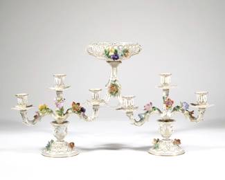 (3pc) DRESDEN PORCELAIN GARNITURE | Comprising a pair of three light candelabra, with blue underglaze Dresden Saxony marks to bottom, and a tall compote, all with applied flower decoration and gilt highlights.  - l. 11.5 x h. 9.25 x dia. 4.5 in. (ea. approx.)


